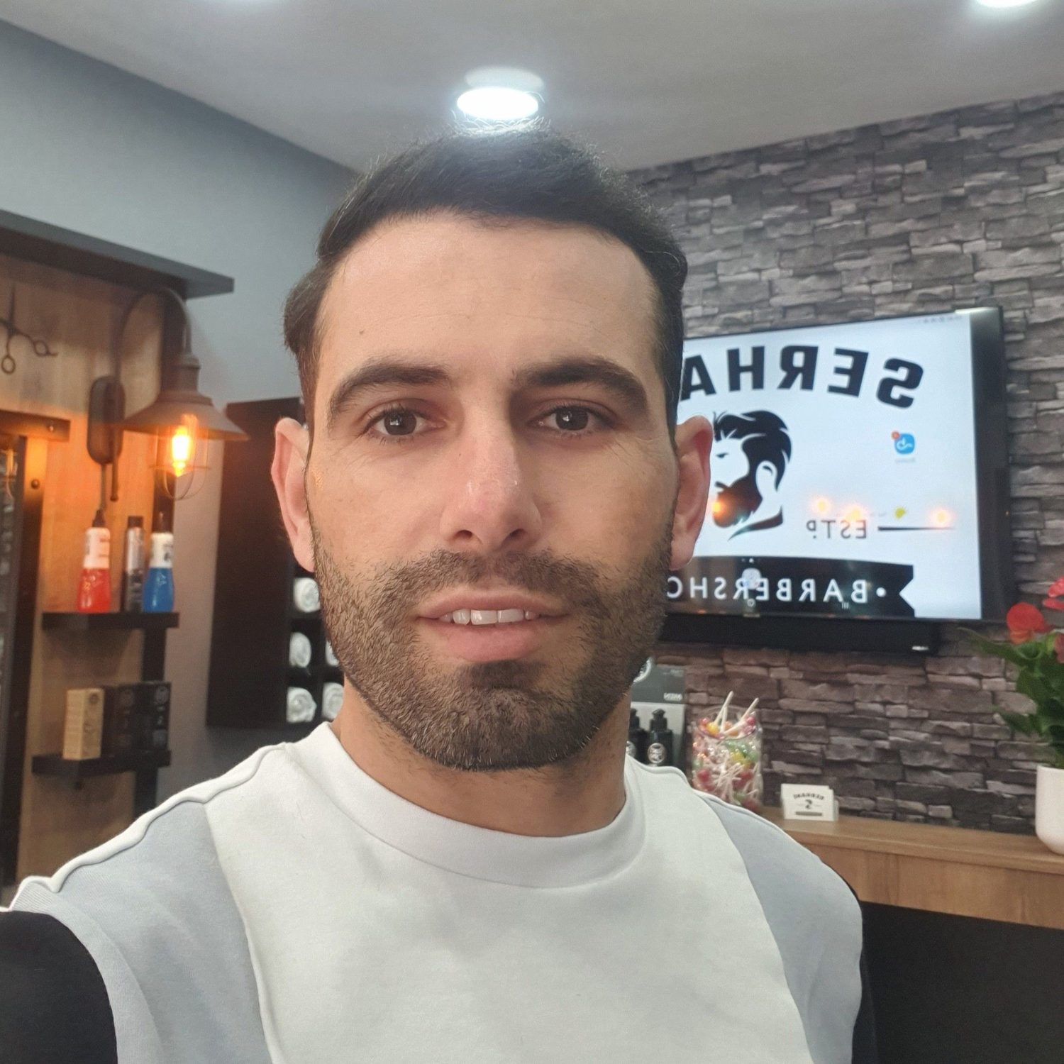 Serhan Duman in the shop, the logo on the screen behind him