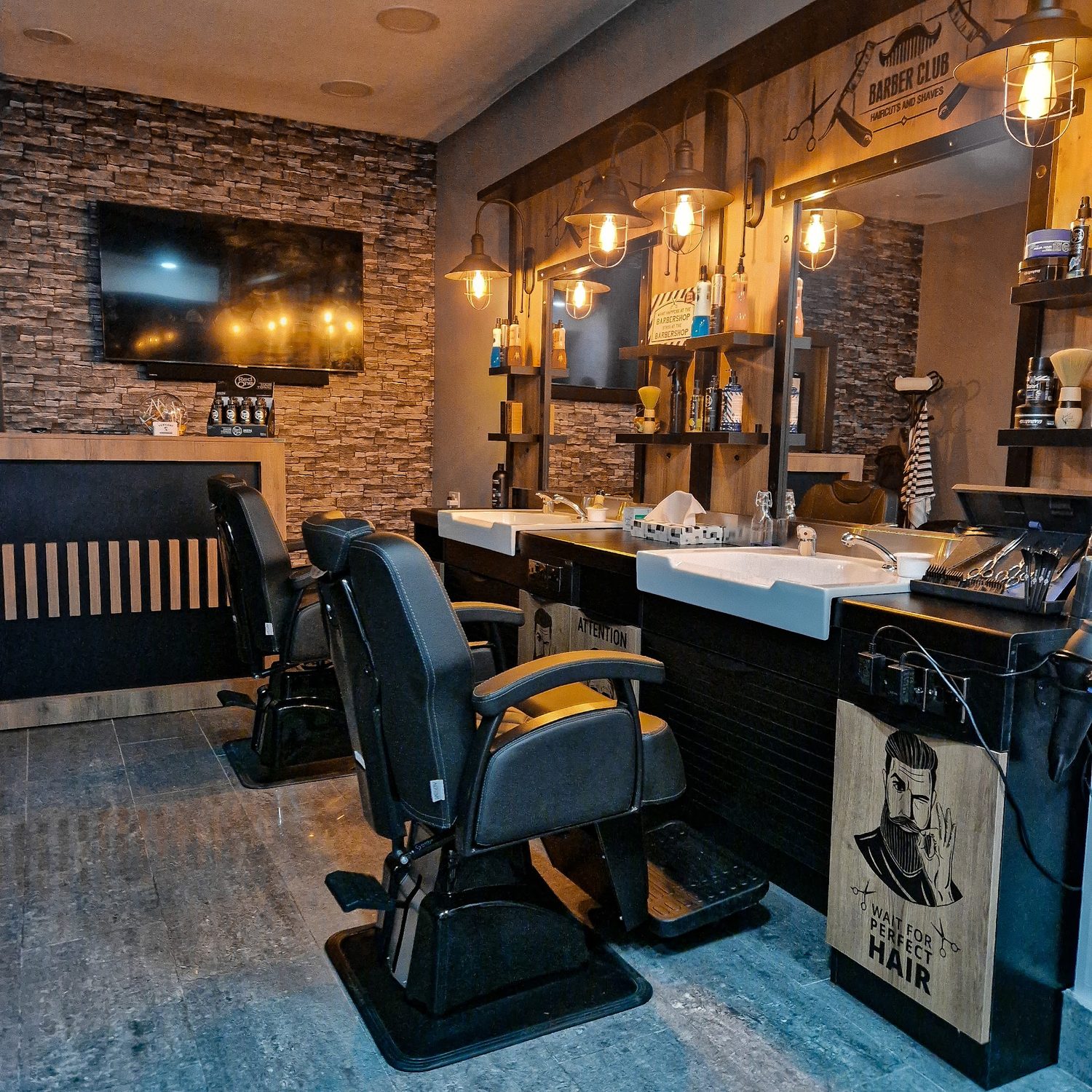 The barber chairs and stations under warm bulb lights